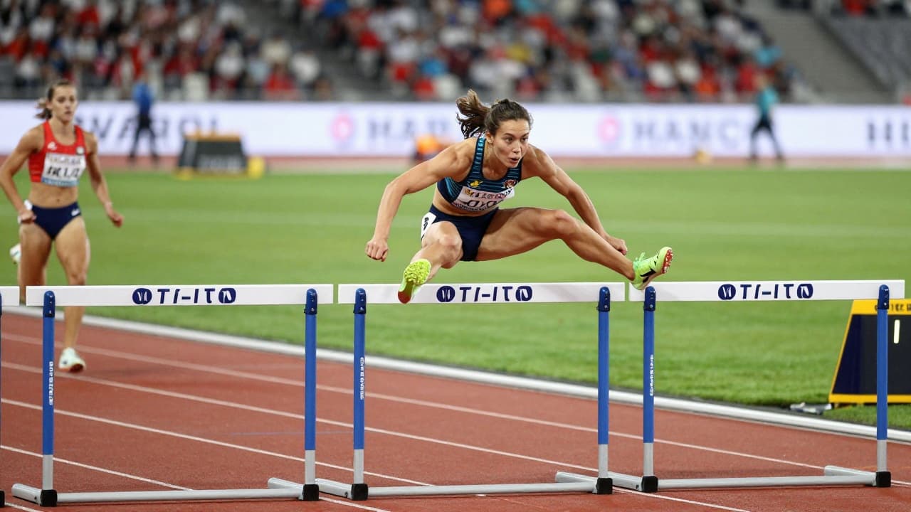 Athlete jumps over a hurdle on the track